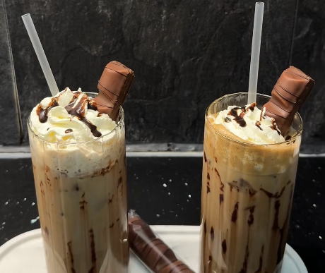 Glas met ijskoffie, slagroom, chocoladeswirl en een stuk Kinder Bueno erbovenop