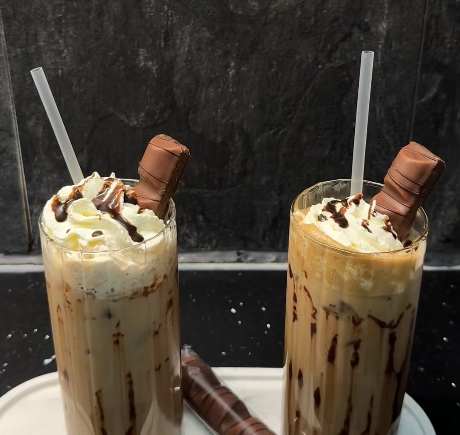 Glas met ijskoffie, slagroom, chocoladeswirl en een stuk Kinder Bueno erbovenop