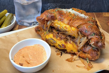 Crispy croissant smash burger met gesmolten cheddar, karamelui en parmezaanse kaas