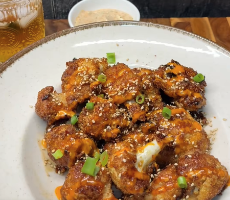 Krokante bloemkool bites uit de oven gegooid in sticky zoet-pittige saus afgemaakt met sriracha mayo en sesamzaadjes